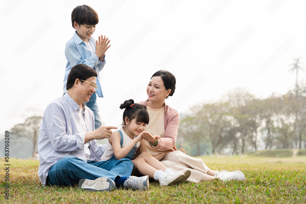 image of an asian family sitting together on the grass at the park image of an asian family sitting together on the grass at the park