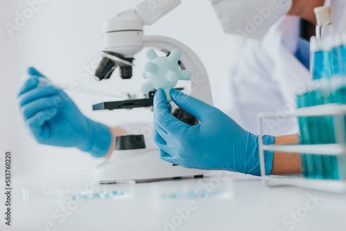 Scientist or doctor wear medical protective mask looking at blood samples under microscope.