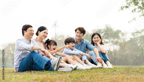 image of an asian family sitting together on the grass at the park