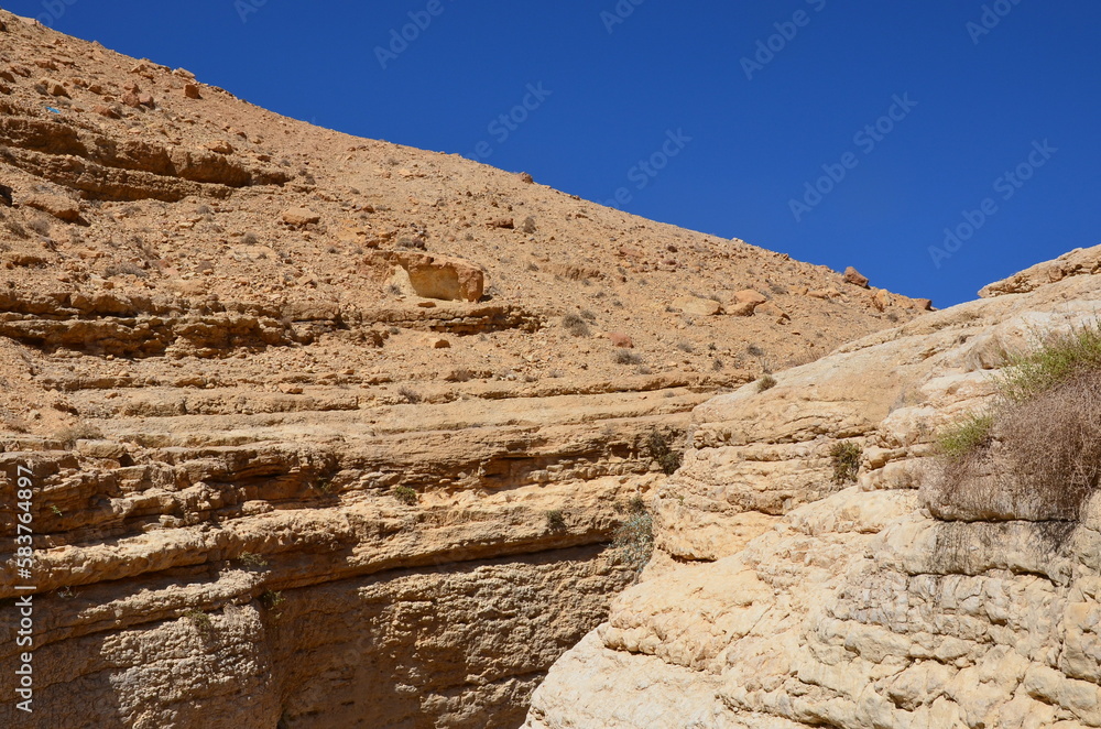 Beautiful rocks and canyons in the wild nature and the dry desert of Wadi Ghweir in Jordan on a bright sunny day