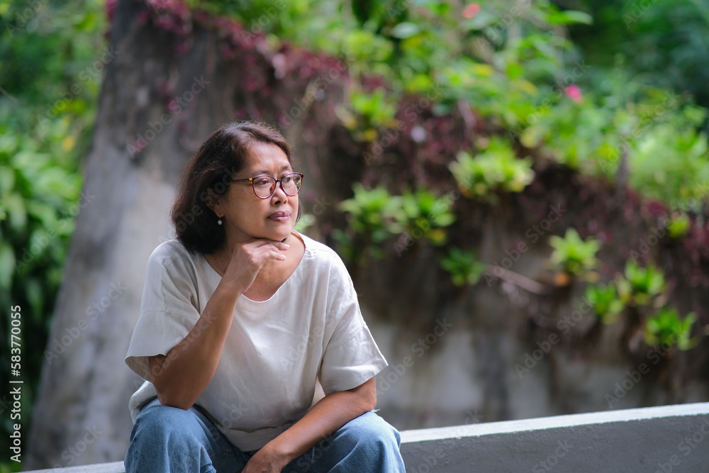Asian woman sitting alone and taking a rest after a long walk in the park Asian woman sitting alone and taking a rest after a long walk in the park