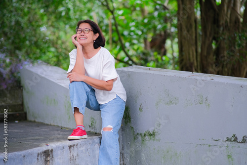 Asian woman sitting alone and taking a rest after a long walk in the park photo