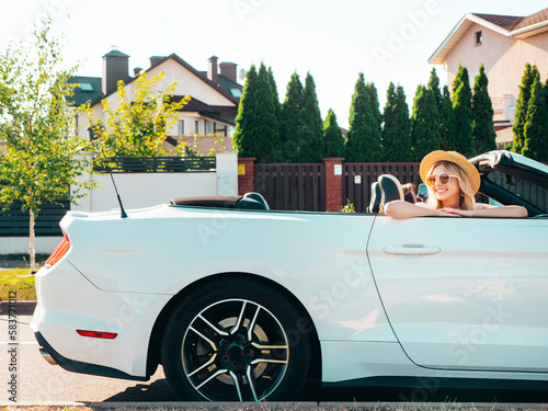 Portrait of two young beautiful and smiling hipster female in convertible car. Sexy carefree women driving. Positive models riding and having fun outdoors. Enjoying summer days. Cheerful and happy © halayalex