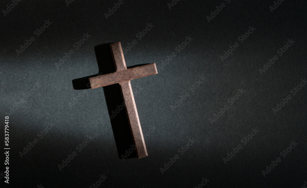 Crucifix wooden cross isolated on dark background. Top view. Copy space.