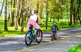 A woman and her son ride bicycles in the park

