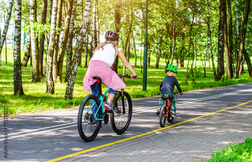 A woman and her son ride bicycles in the park 