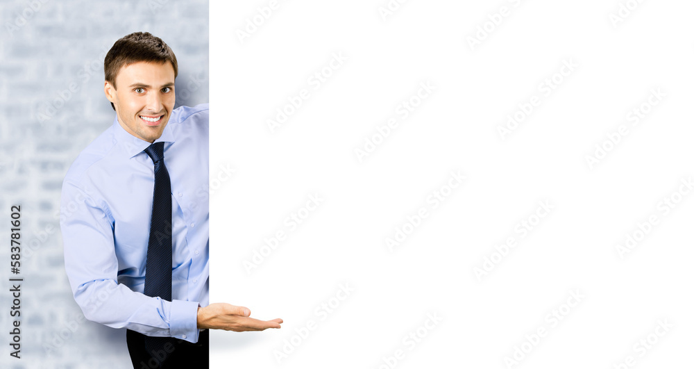 Portrait picture of young business man bank manager in confident cloth, necktie stand behind show empty white banner signboard billboard with copy space text area. White bricks wall background Portrait picture of young business man bank manager in confident cloth, necktie stand behind show empty white banner signboard billboard with copy space text area. White bricks wall background