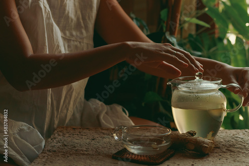 Woman preparing a pot of ginger infusion as part of a healthy morning routine, showing slow living, wellness and holistic healing