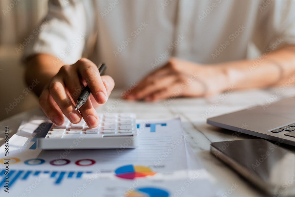 Close up of businessman hands working on calculator to calculate financial data report, accounting documents and laptop computer at office, business concept Close up of businessman hands working on calculator to calculate financial data report, accounting documents and laptop computer at office, business concept