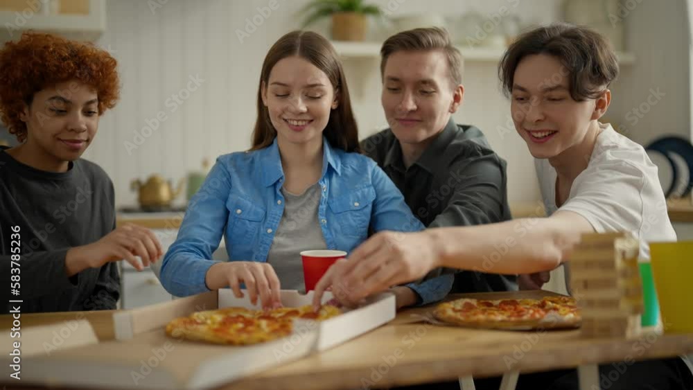 Hungry friends, students enjoying huge delicious pizza at kitchen home, open package and take piece. Food delivery service. Tasty fast food. Meeting, communication at weekend. Rest at company friends. Hungry friends, students enjoying huge delicious pizza at kitchen home, open package and take piece. Food delivery service. Tasty fast food. Meeting, communication at weekend. Rest at company friends.