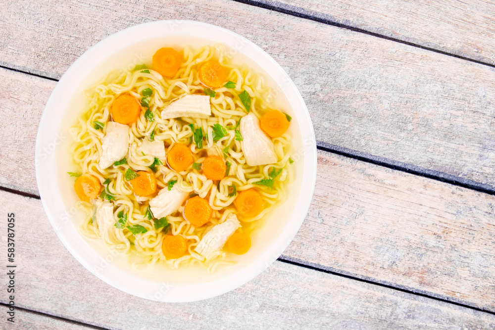 Homemade chicken soup with noodles and vegetables in a white bowl, on a wooden background. Homemade chicken soup with noodles and vegetables in a white bowl, on a wooden background.