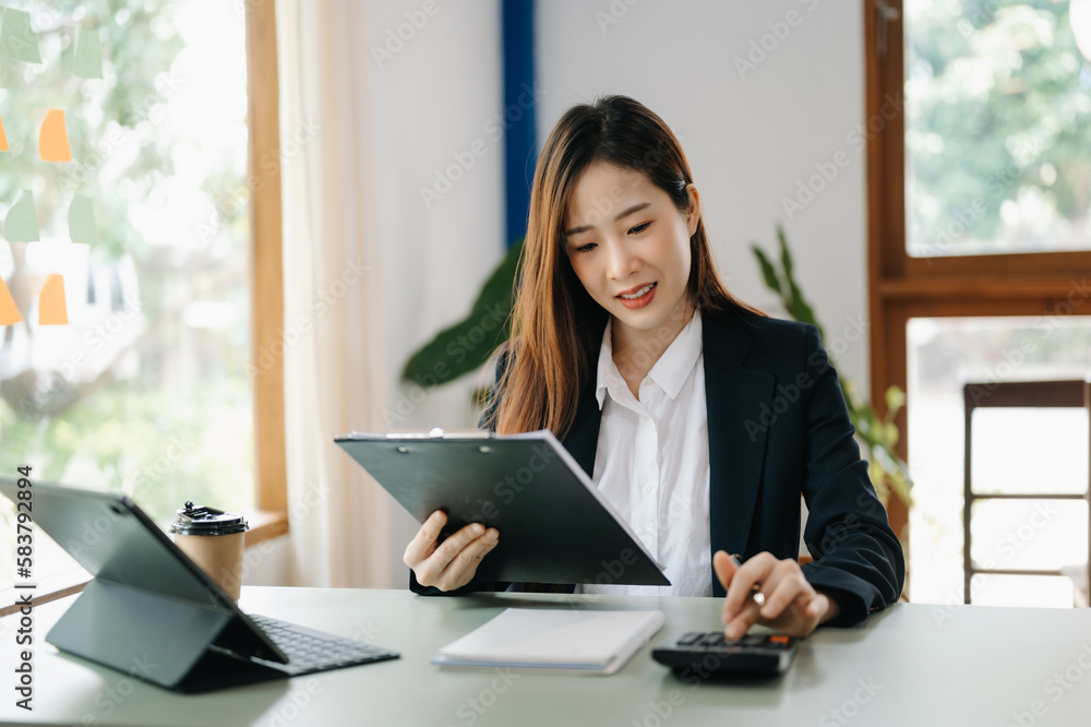 Beautiful Asian business woman typing laptop and tablet Placed at the table at the office.. Beautiful Asian business woman typing laptop and tablet Placed at the table at the office..