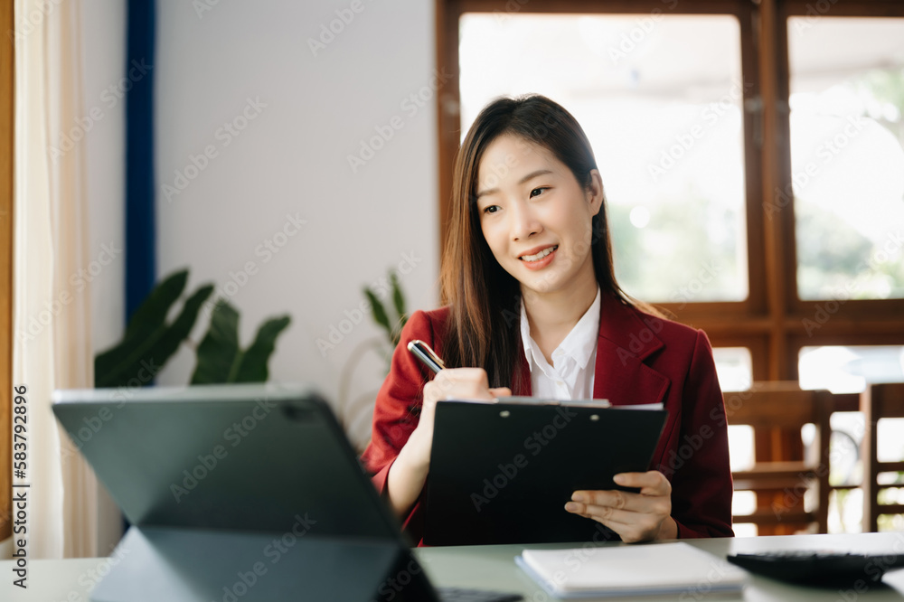 Beautiful Asian business woman typing laptop and tablet Placed at the table at the office.. Beautiful Asian business woman typing laptop and tablet Placed at the table at the office..