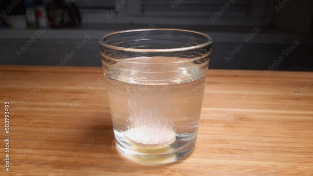 Dissolving start of effervescent tablet in water glass, side view Dissolving start of effervescent tablet in water glass, side view