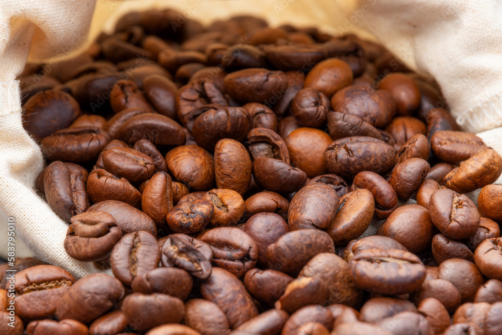Fototapeta premium Roasted coffee beans and sack bag background. Selective focus, Dark and Moody wallpaper.