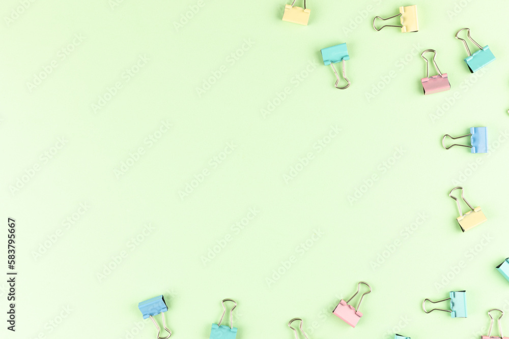 Colorful binder clips on green background, flat lay. Space for text Colorful binder clips on green background, flat lay. Space for text