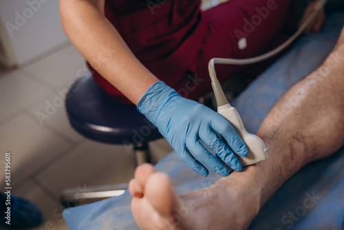 Fototapeta Naklejka Na Ścianę i Meble -  closeup hand of woman doctor doing an ultrasound of the legs of a man and knee