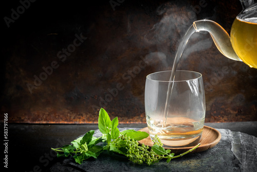 Herbal tea in a cup with basil leaves on rustic wooden table. Basil is food and herb for healthy.