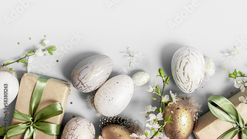 Photography beautiful light easter layout with eco-wrapped gifts, golden and marble eggs, cherry blossoms and confetti on a white background