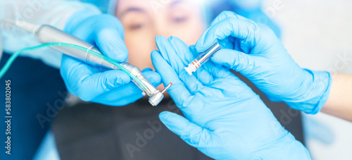 Closeup photo of dental implant in dentist hands with female patient in dental chair behind.