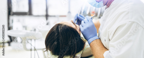 Dentist with patient in dental chair providing manipulations in oral cavity.