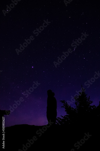 Silhouette of a person looking at the stars in the dark sky.