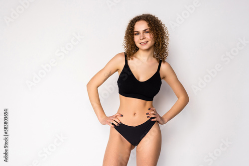 Cheerful attractive young fitness woman in black top and black lingerie over white background © F8  \ Suport Ukraine
