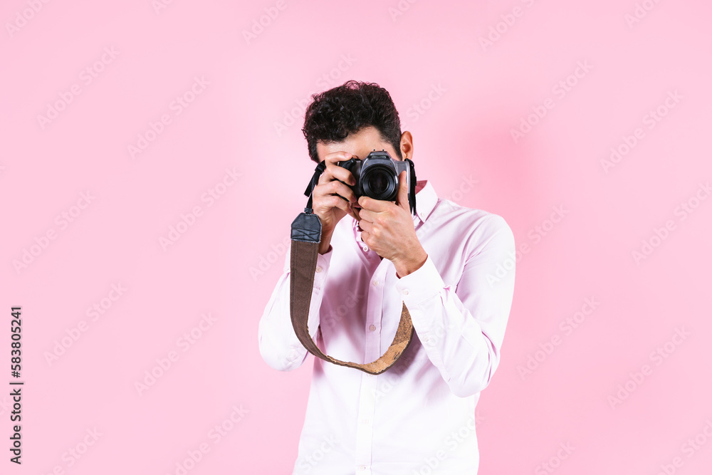 portrait of young hispanic man using a camera to take photos on pink background in Mexico Latin America portrait of young hispanic man using a camera to take photos on pink background in Mexico Latin America