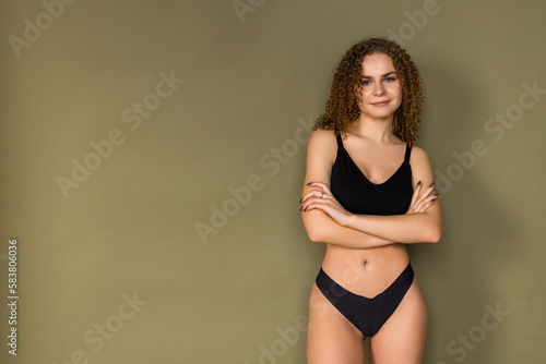 Figure of a attractive woman posing on black lingerie isolated on khaki background