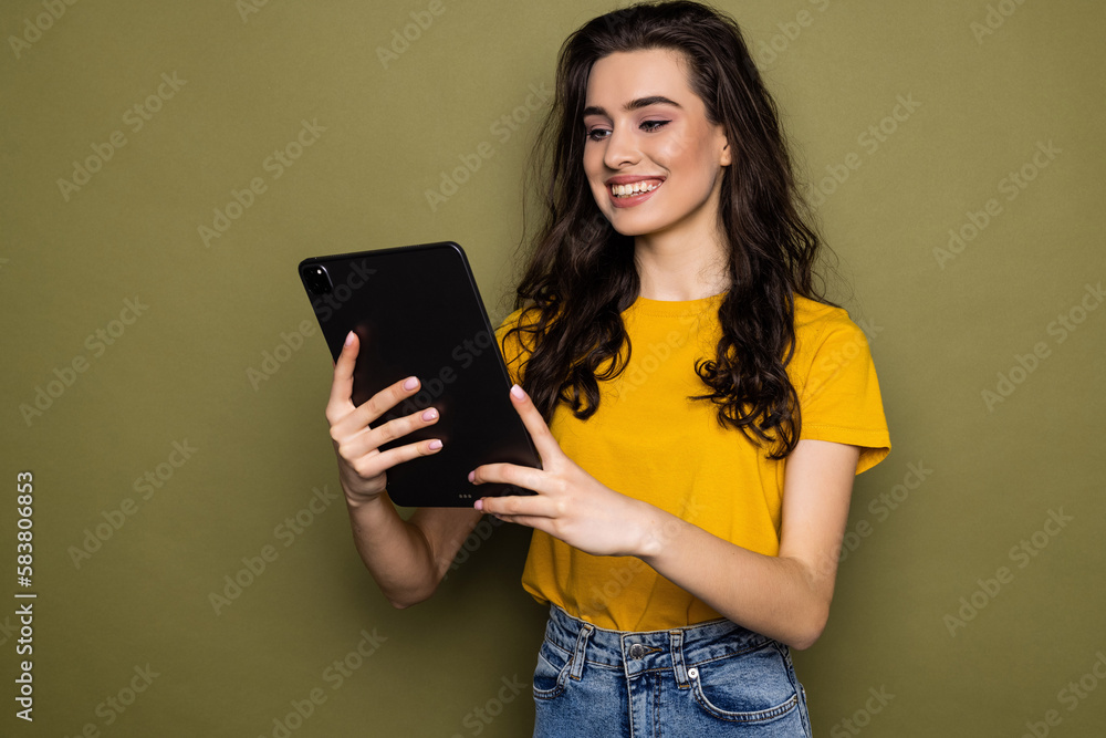 Photo of young woman hold tablet isolated on khaki color background Photo of young woman hold tablet isolated on khaki color background