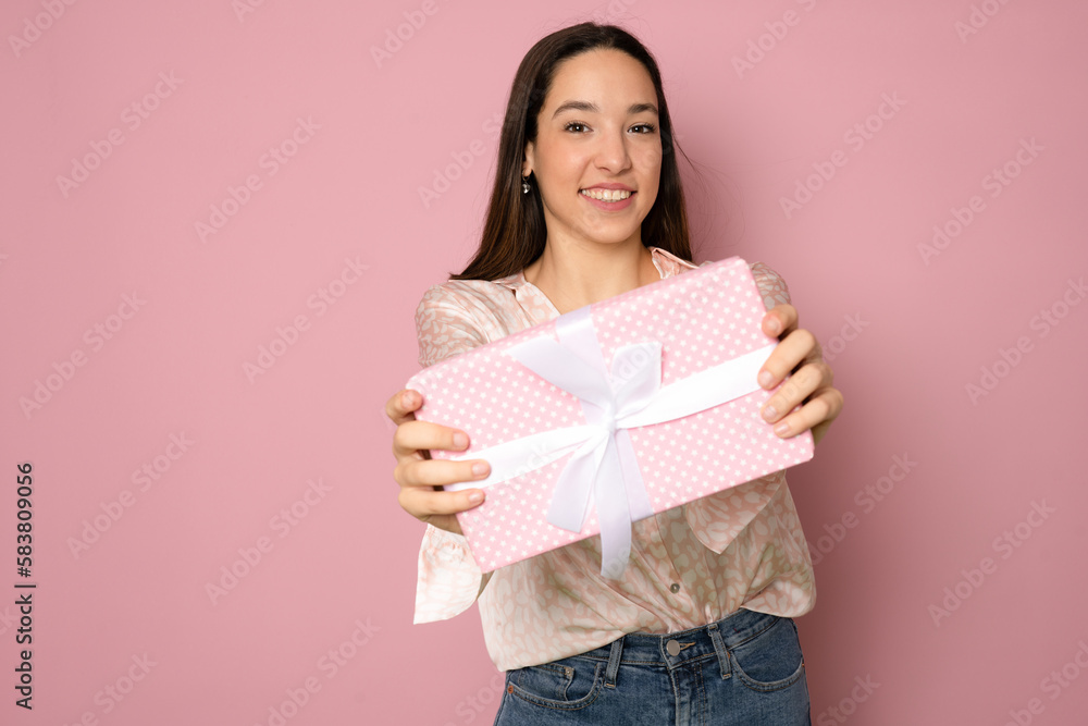 Close-up portrait of happy exited pretty brunette woman holding gift box, looking at camera, isolated on pink background Close-up portrait of happy exited pretty brunette woman holding gift box, looking at camera, isolated on pink background
