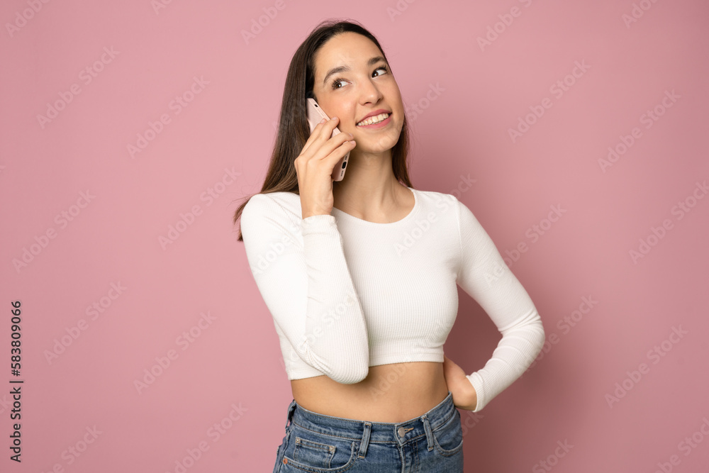 Young woman over isolated pink background keeping a conversation with the mobile phone with someone Young woman over isolated pink background keeping a conversation with the mobile phone with someone