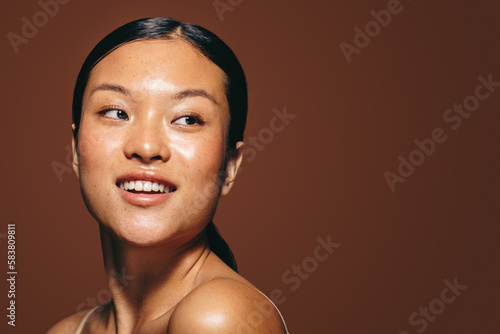 Radiant in the studio, a young woman in her 20’s stands with flawless skin