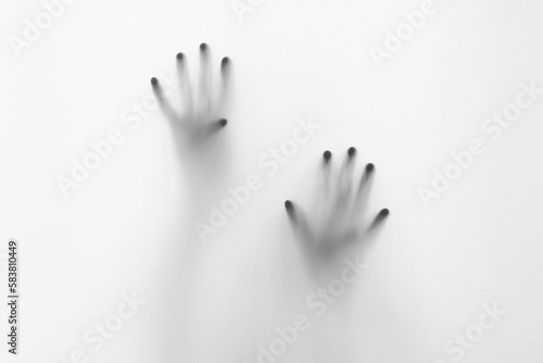 Defocused hand silhouette behind frosted glass in black and white mode, halloween concept