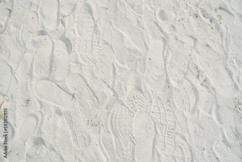 Many footwear footprints on white sand of the beach. Full frame. Surface and texture background.