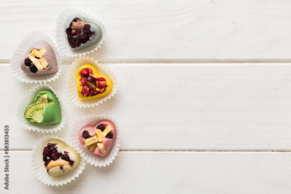 chocolate sweets in the form of a heart with fruits and nuts on a colored background. top view with space for text, holiday concept chocolate sweets in the form of a heart with fruits and nuts on a colored background. top view with space for text, holiday concept