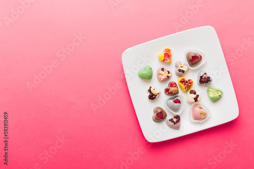 Plate with different chocolate on colored background. Assortment of fine chocolates top view vith copy space Health and obesity concept
