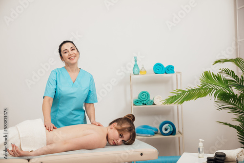 masseur massages the client's back in the massage room