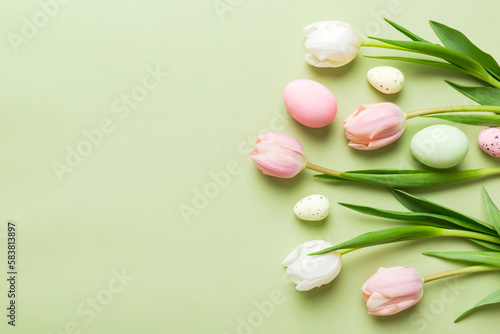 Happy Easter composition. Easter eggs on colored table with yellow Tulips. Natural dyed colorful eggs background top view with copy space © sosiukin