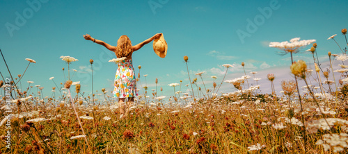 Fotografie Pretty woman with colorful dress and hat in a flowers field- happiness,  freedom
