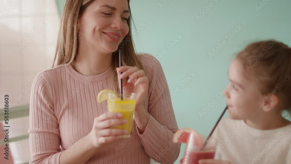 Mother and daughter having good time during breakfast with fresh squeezed juices in the cafe Mother and daughter having good time during breakfast with fresh squeezed juices in the cafe