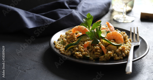 Insalata di farro con zucchine, gamberi e pesto di basilico su sfondo scuro. Cibo sano, cibo vegetariano. Copia spazio. photo