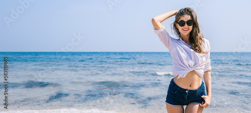 Portrait of beautiful caucasian woman in white shirt and jeans on tropical beach. Portrait of happy young girl relax at sea. Tanned skin girl walking on beach. Holiday lifestyle casual girl next door. photo