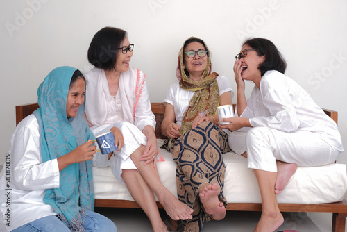 Four women sitting in the sofa sharing some funny stories together photo