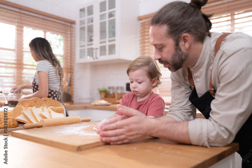 Mom and dad in the kitchen of the house with their small children. Have a good time baking bread and making dinner together. Mom and dad in the kitchen of the house with their small children. Have a good time baking bread and making dinner together.