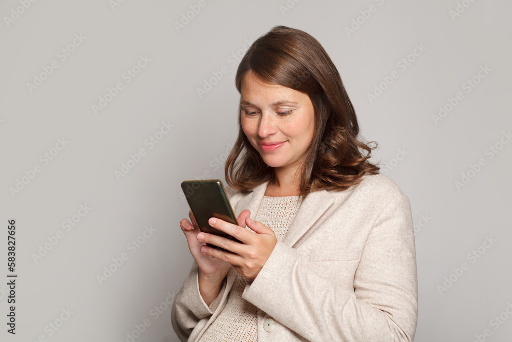 Happy charming pregnant woman using mobile phone on grey background Happy charming pregnant woman using mobile phone on grey background
