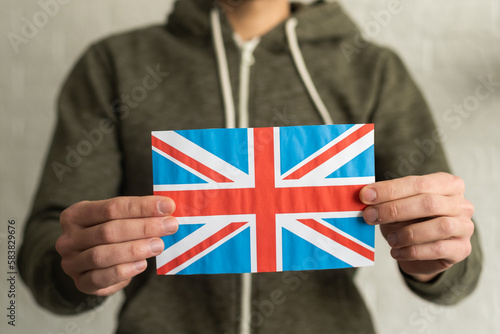 Hand holding flag of UK, isolated on white background