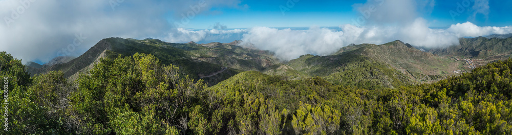 Panoramic view from Baracan mountain. Green forest, hills and valley with terraced fields and village Las Portelas at Park rural de Teno, Tenerife, Canary Islands, Spain. sunny day, blue sky