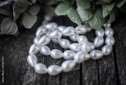 Natural freshwater pearls of various shapes and colors are photographed on a wooden board.