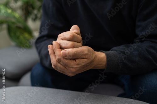 Worried religious senior man praying to god with his hands raised and touching as he looks beseechingly towards heaven for help and inspiration.